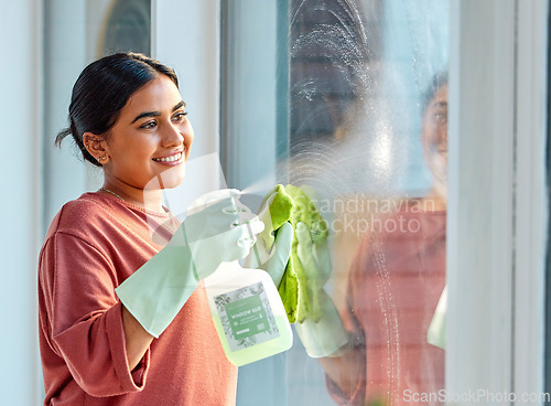 Image of Glass, spray or woman cleaning a window with liquid soap or chemical product for dusty bacteria or germs at home. Cleaning services, dirty or happy Indian girl cleaner washing glass door with a cloth