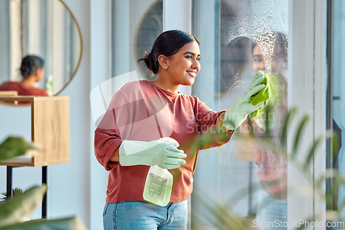 Image of Woman, cleaning and window st home for dirt, dust and bacteria with a cloth and spray bottle for shine and clean view. Happy female cleaner or maid with a smile using chemical on apartment glass