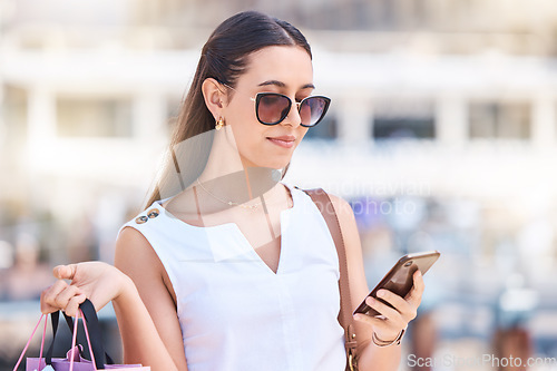 Image of Woman, shopping bag and phone in city street for social media, searching store location or reading retail discounts online. Fashion shopping, 5g mobile communication and stylist or customer promo