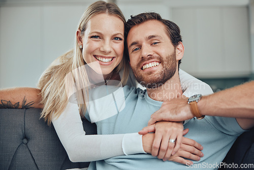 Image of Couple, sofa and portrait for hug, smile and love for romance, relax and holding hands in living room. Happy couple, man and woman with embrace by couch, lounge and happiness at house in Los Angeles