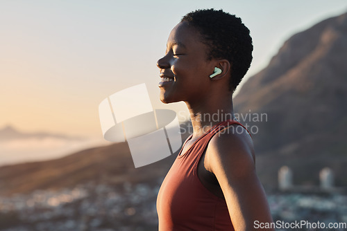 Image of Headphones, fitness or zen black woman on a mountain for peaceful, calm and breathing in relaxing fresh air. Breathe, healthy or happy sports athlete with smile streaming radio music, song or podcast