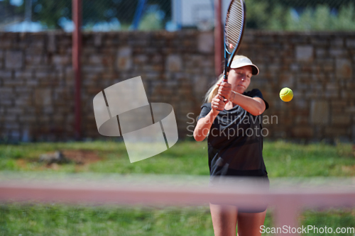 Image of A young girl showing professional tennis skills in a competitive match on a sunny day, surrounded by the modern aesthetics of a tennis court.