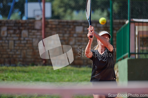 Image of A young girl showing professional tennis skills in a competitive match on a sunny day, surrounded by the modern aesthetics of a tennis court.