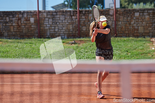 Image of A young girl showing professional tennis skills in a competitive match on a sunny day, surrounded by the modern aesthetics of a tennis court.