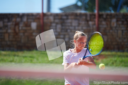 Image of A young girl showing professional tennis skills in a competitive match on a sunny day, surrounded by the modern aesthetics of a tennis court.