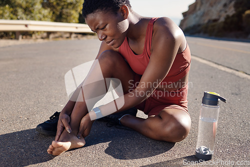 Image of Black woman, runner and foot injury outdoor, pain and training on road, marathon and water bottle. African American female, girl and athlete with discomfort on heel, suffering and agony for fitness.