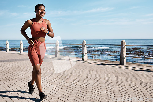 Image of Black woman running at beach promenade for fitness, energy and strong summer body. Runner, healthy female and sports wellness at ocean for marathon goals, cardio exercise and workout in sunshine