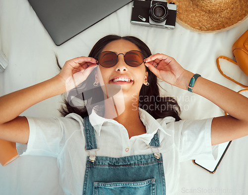 Image of Travel packing, woman and happiness of a person with sunglasses on a hotel bed ready for adventure. Clothing, technology and suitcase pack break with a solo traveler above view happy about journey