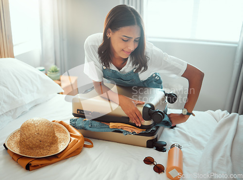 Image of Woman, overloaded suitcase and luggage bag in bedroom for travel, vacation and international journey, holiday and trip. Female tourist struggle to close baggage full of clothing, packing and problem