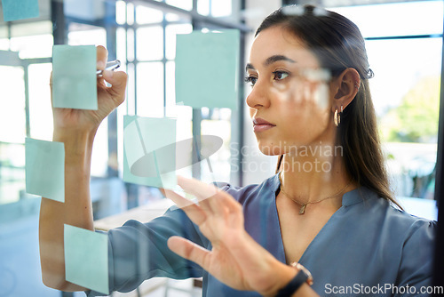 Image of Corporate woman, sticky notes and glass board for planning, brainstorming and strategy at modern office. Marketing expert, thinking and idea for innovation, writing and vision at office in Barcelona