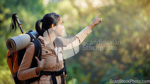 Image of Hiker, exercise and backpacking with a woman in nature for adventure and carefree freedom. Backpack, hiking and view with a female pointing while in a forest to hike while on a natural environment