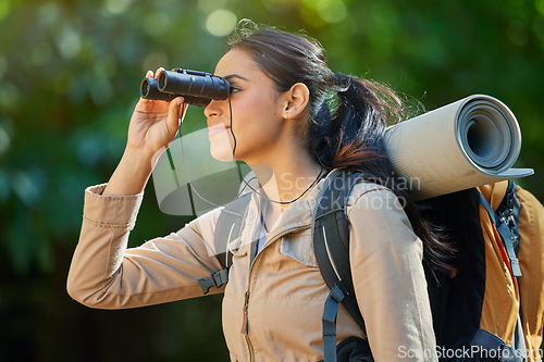 Image of Woman hiking, binocular and vision in forest with backpack, camping gear and smile on nature journey. Happy hiker girl, bird watching and trekking in woods for adventure, fitness and health in Amazon