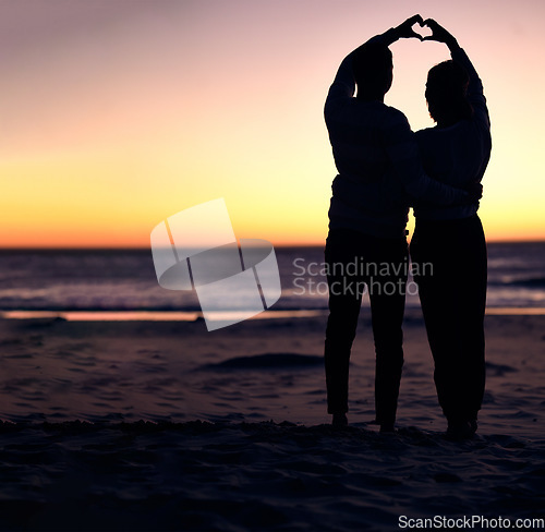 Image of Couple, sunset silhouette and beach with heart sign hands, bonding and love on vacation for honeymoon. Man, woman and romantic hand signal by ocean with dusk sunshine for romance together in nature