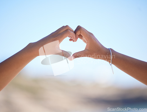 Image of Hands together, heart sign and outdoor at beach, nature and blue sky in blurred background for love. Couple, hand touch and romantic gesture for bonding, care and support for relationship in Miami