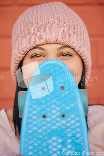 Image of Skateboard, young face and woman hiding with winter beanie, clothes and gen z fashion, hipster culture and happiness in city. Portrait, happy and shy skater girl, eyes and relax for fun at skate park