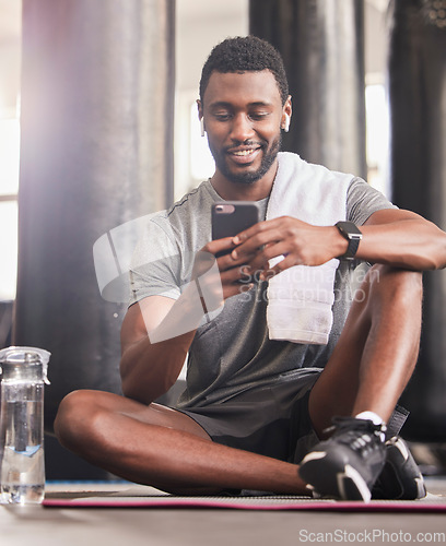 Image of Fitness, phone and black man relax and smile for online communication, sports workout or watching exercise tutorial in gym. Happiness, training wellness video on mobile and rest after cardio run