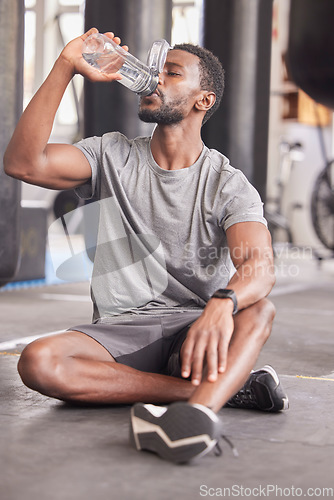 Image of Black man drink water, fitness and gym with challenge workout training for muscle and thirsty with motivation, goals and sweating. Tired sports, athlete person with water bottle in health exercise