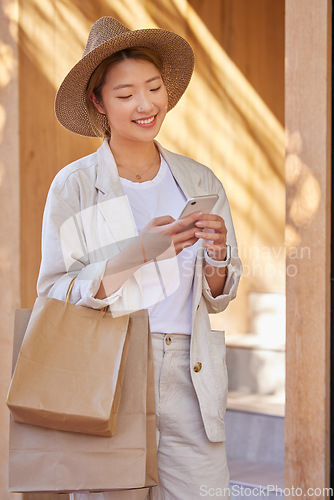 Image of Woman, shopping bag and phone for communication, ecommerce and online chat about sale, discount and savings while outdoor. Happy customer or asian female with smartphone for banking and retail coupon