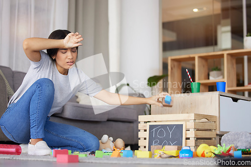 Image of Toys, mother tired and headache for cleaning, messy living room and exhausted. Woman, clean playthings and female stress, frustrated and upset in lounge, annoyed and overworked in home with disorder.