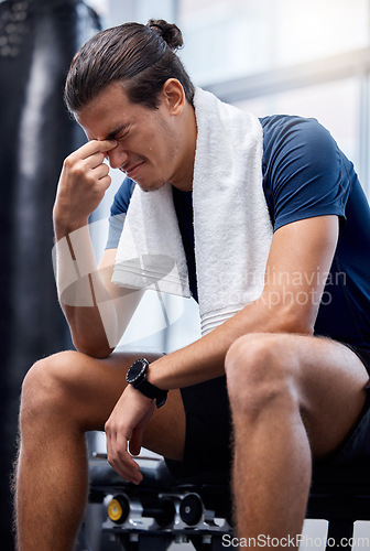 Image of Man, gym exercise and tired with headache at training, workout or wellness studio with anxiety. Bodybuilder, fitness and burnout while sitting for stress, rest or relax after weightlifting in Toronto