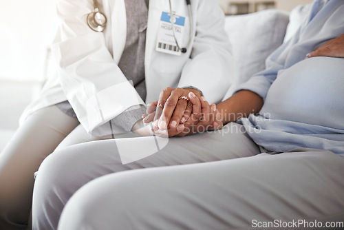 Image of Healthcare, doctor sitting and holding hands with pregnant woman on sofa for care, trust and support in medicine. Gynecologist, woman and pregnancy, helping hands encourage new mother with empathy.