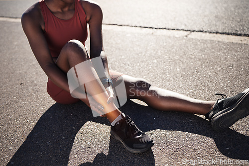 Image of Leg, injury and pain with a sports black woman holding her ankle outdoor during a fitness workout from above. Ankle, sprain or exercise with a female runner or athlete suffering from an injured joint