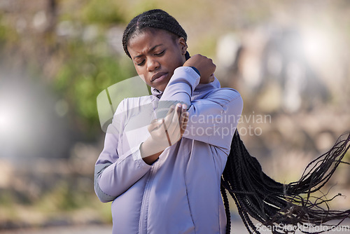 Image of Fitness, black woman and elbow injury during exercise, training and cardio outdoor with lens flare in a park. Arm pain, injured or hurt by athlete running in nature for marathon, practice and unhappy