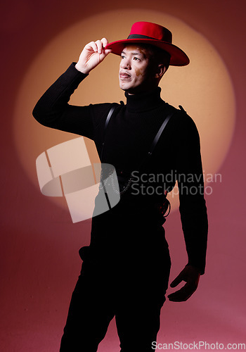 Image of Fashion, style and man with vitiligo in a studio with a grungy, edgy and goth outfit with an orange light. Stylish, aesthetic and cool male model with a skin depigmentation posing by a red background