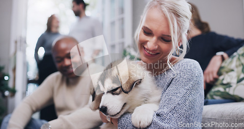 Image of Friends, family and woman with puppy in living room at Christmas party in family home. Friendship, diversity and dog love, happy woman with smile and new pet at holiday celebration in apartment.