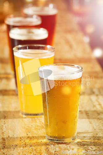 Image of Alcohol, beer and glasses at a bar table for party, club and happy hour promotion, sale and commercial background for event. Social lifestyle, drink and group of ale glasses at pub for cocktail sale