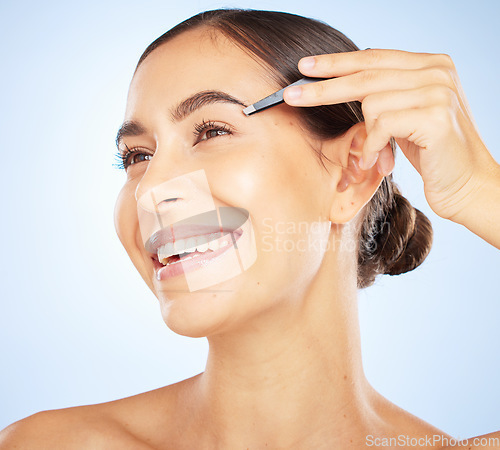 Image of Face, beauty and woman with tweezers in studio isolated on a blue background. Makeup, skincare or hair care of female model with product for eyebrow and hair removal for hygiene, grooming or wellness