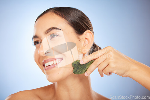 Image of Skincare, beauty and woman with gua sha in studio on blue background for wellness, healthy skin and glow. Dermatology, spa aesthetic and girl with stone for facial treatment, cosmetics and exfoliate