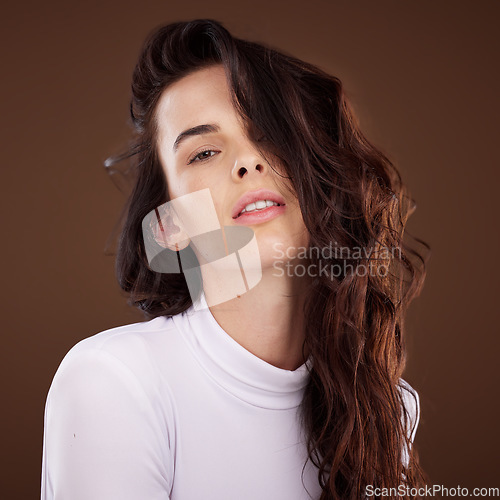 Image of Portrait, hair and beauty with a model woman in studio on a brown background for natural or keratin treatment. Face, hair care and luxury with an attractive young female posing to promote haircare