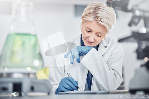 Image of Science, research and senior woman writing notes on documents in laboratory. Innovation, thinking and elderly female scientist researching, recording and write experiment results, analysis or report.