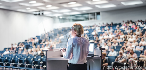 Image of Female speaker giving a talk on corporate business conference. Unrecognizable people in audience at conference hall. Business and Entrepreneurship event.