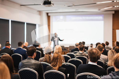 Image of Speaker giving a talk in conference hall at business event. Rear view of unrecognizable people in audience at the conference hall. Business and entrepreneurship concept.