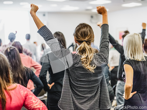 Image of Participants of interactive motivational speech feeling empowered and motivated, hands raised high in the air.