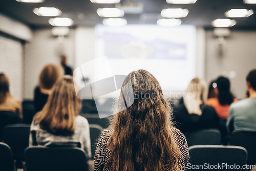 Image of Speaker giving a talk in conference hall at business event. Rear view of unrecognizable people in audience at the conference hall. Business and entrepreneurship concept.