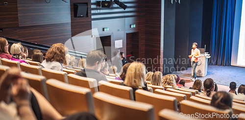 Image of Speaker giving a talk in conference hall at business event. Rear view of unrecognizable people in audience at the conference hall. Business and entrepreneurship concept.