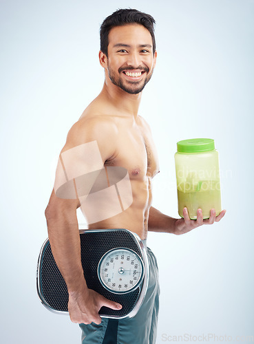 Image of Man, diet or body protein powder on blue studio background in weight loss, bodybuilding or Japanese muscle growth. Portrait, smile or happy athlete with weight scale or healthcare wellness supplement