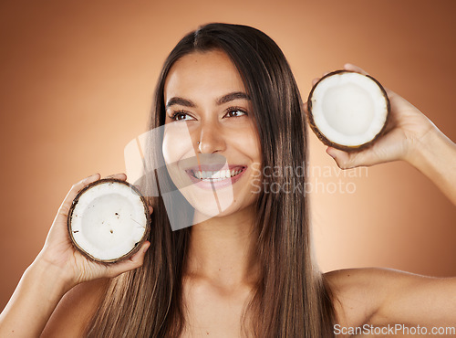 Image of Woman, skincare and coconut in studio, happy or smile for self care, nutrition or cosmetic health. Model, skin wellness and fruit for oil, moisturizer or cosmetics background for natural radiant glow