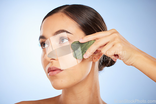 Image of Skincare, beauty and woman with gua sha in studio on blue background for wellness, healthy skin and glow. Dermatology, spa aesthetic and girl with stone for facial treatment, cosmetics and exfoliate