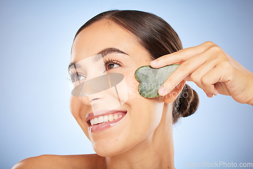 Image of Skincare, beauty and woman with gua sha in studio on blue background for wellness, healthy skin and glow. Dermatology, spa aesthetic and girl with stone for facial treatment, cosmetics and exfoliate