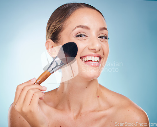 Image of Face portrait, skincare and woman with makeup brush in studio isolated on a blue background. Product, cosmetics tool and aesthetics of happy female model with accessory to apply foundation for beauty