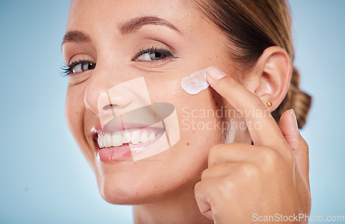 Image of Skincare, beauty and portrait of a woman with face cream for health, wellness and natural face routine. Cosmetic, happy and model with facial lotion, spf or creme isolated by a blue studio background