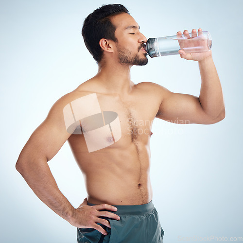 Image of Fitness, health or man drinking water in studio after training in workout or exercise for body goals or wellness. Motivation, weight loss or tired healthy person relaxing and drinks liquid or bottle