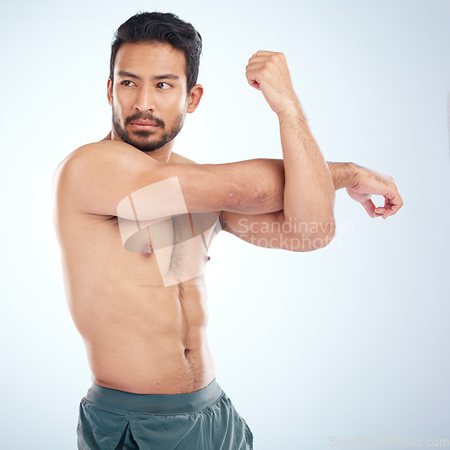 Image of Health, fitness and man stretching arm for flexibility in studio isolated on a blue background. Thinking, sports and young male athlete, warm up and getting ready for training, exercise and workout.