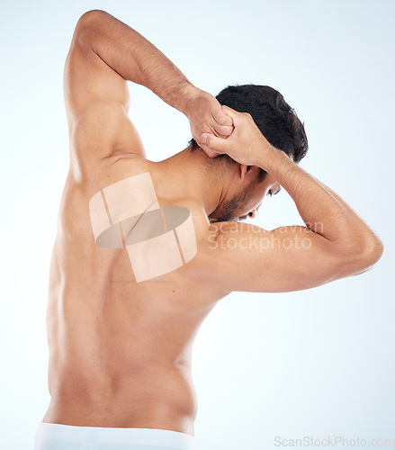 Image of Man, body or stretching back muscle on blue background in studio for relief, training and wellness. Sports athlete, fitness model or strong man and bodybuilder flexing for workout goals