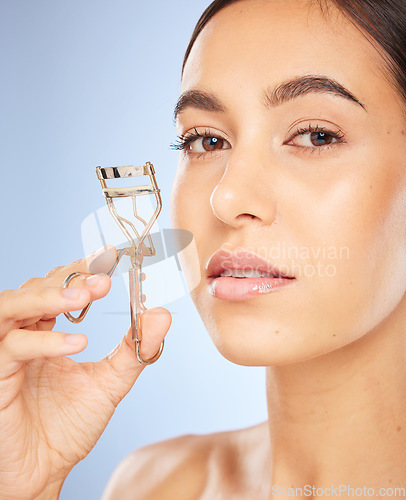 Image of Face, beauty and woman with eyelash curler in studio isolated on a blue background. Portrait, skincare and makeup cosmetics of female model with metal tool or product to curl eyelashes for aesthetics