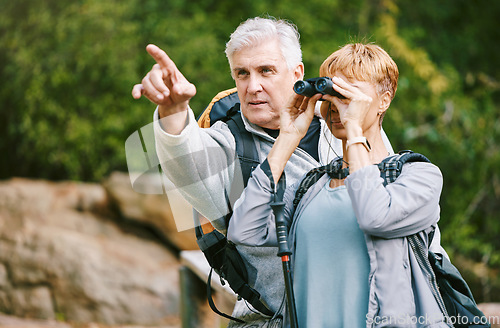 Image of Elderly, couple hiking and fitness, adventure outdoor with hike together, active lifestyle with freedom and travel. Nature, trekking and senior man pointing and woman with binocular for bird watching